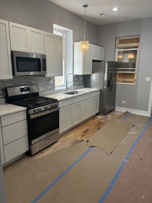 kitchen with decorative light fixtures, stainless steel appliances, white cabinetry, and sink