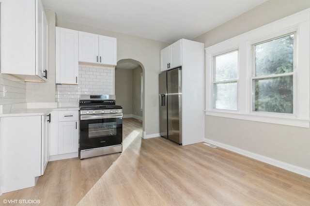 kitchen with decorative backsplash, white cabinets, light hardwood / wood-style floors, and appliances with stainless steel finishes