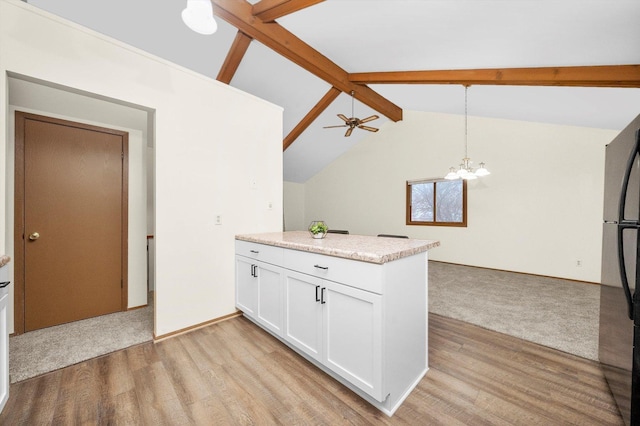 kitchen with pendant lighting, lofted ceiling with beams, refrigerator, ceiling fan with notable chandelier, and white cabinetry