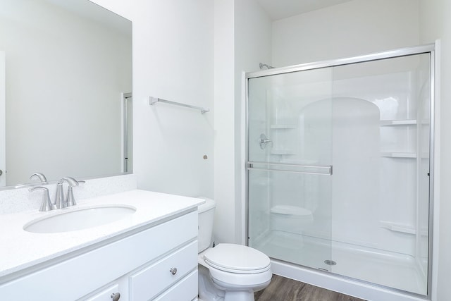 bathroom with wood-type flooring, vanity, an enclosed shower, and toilet