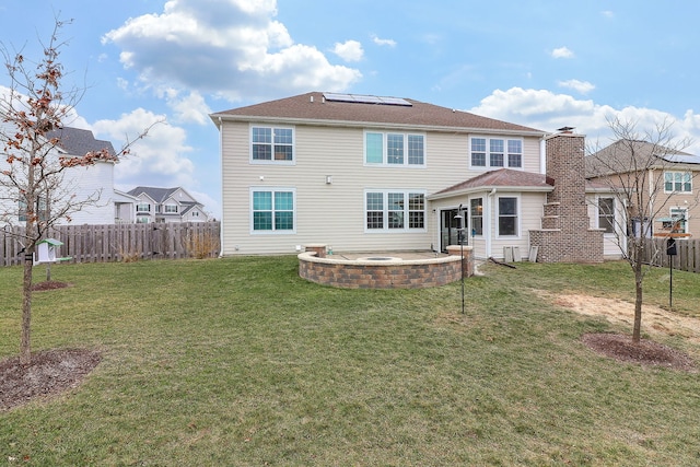 rear view of property with solar panels, a patio, and a lawn