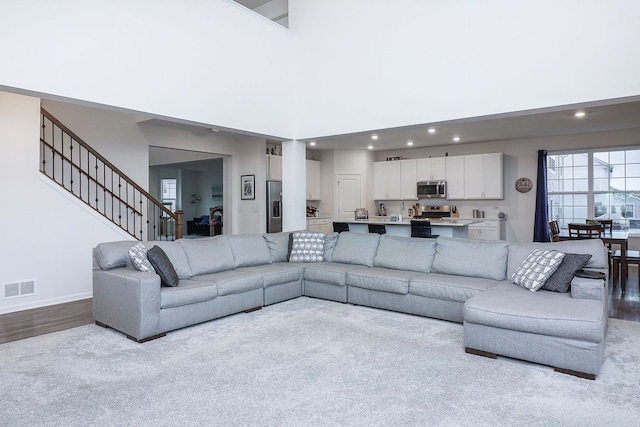 living room featuring light colored carpet and a high ceiling