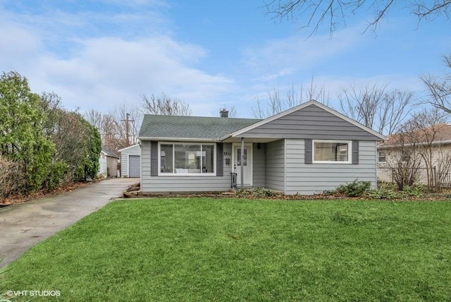 ranch-style house featuring a front yard, a garage, and an outbuilding