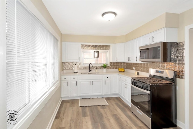 kitchen featuring stainless steel appliances, sink, white cabinets, and backsplash