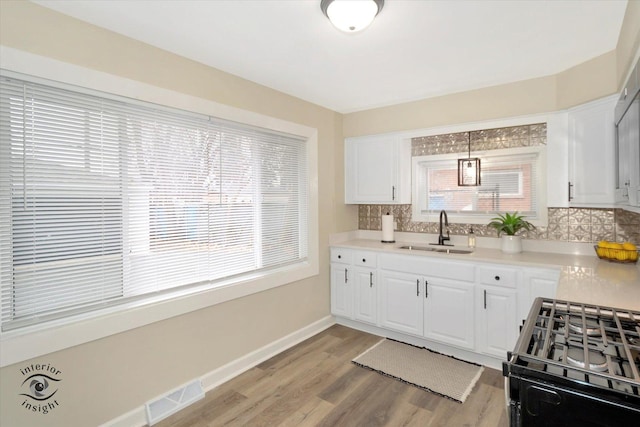 kitchen with white cabinetry, sink, black range oven, and decorative light fixtures