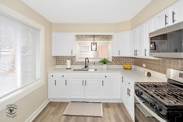 kitchen with sink, backsplash, stainless steel appliances, white cabinets, and decorative light fixtures