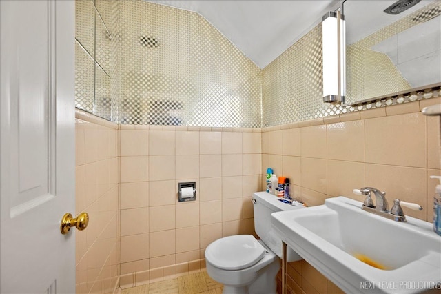 bathroom with tile patterned flooring, sink, tile walls, and vaulted ceiling