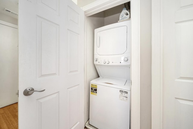 washroom with wood-type flooring and stacked washer / dryer