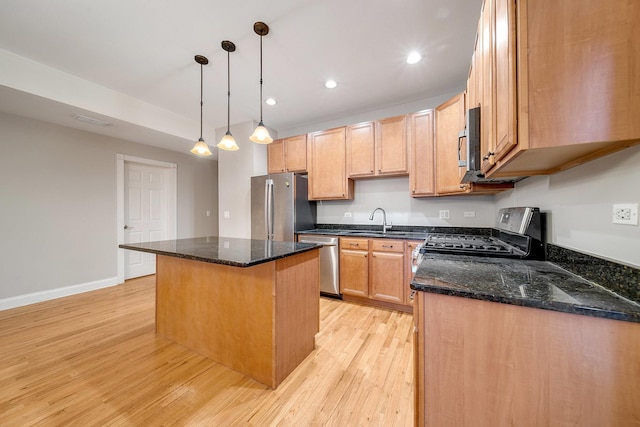 kitchen featuring a kitchen island, sink, dark stone countertops, hanging light fixtures, and stainless steel appliances