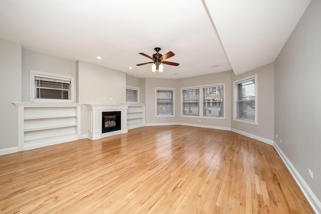 unfurnished living room featuring ceiling fan, light hardwood / wood-style floors, and built in shelves