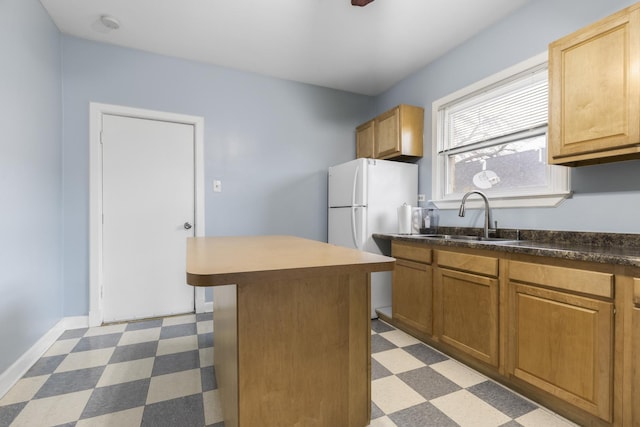 kitchen with white refrigerator, a kitchen island, and sink