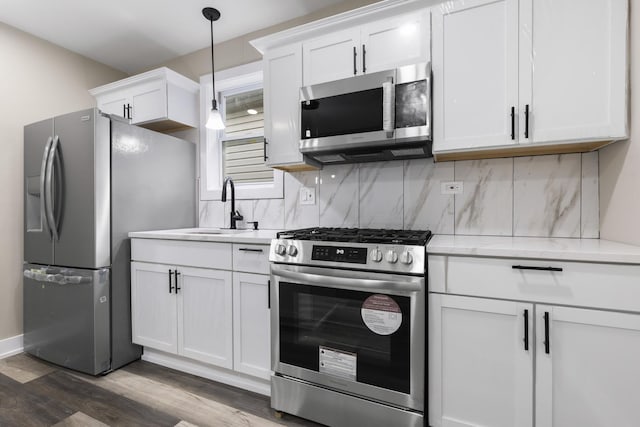 kitchen featuring sink, hanging light fixtures, stainless steel appliances, dark hardwood / wood-style flooring, and white cabinets