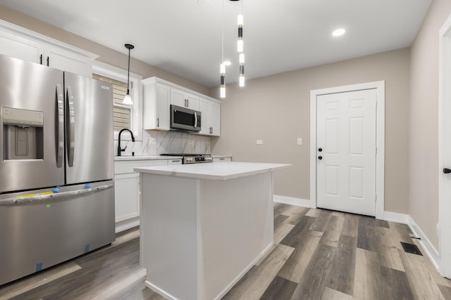 kitchen with pendant lighting, a center island, white cabinets, and appliances with stainless steel finishes