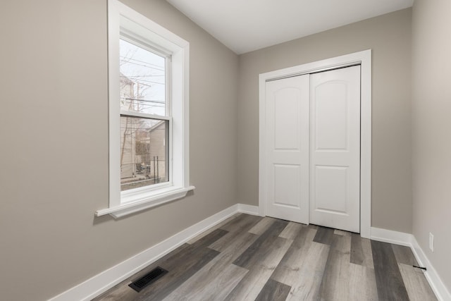 unfurnished bedroom with dark hardwood / wood-style flooring and a closet