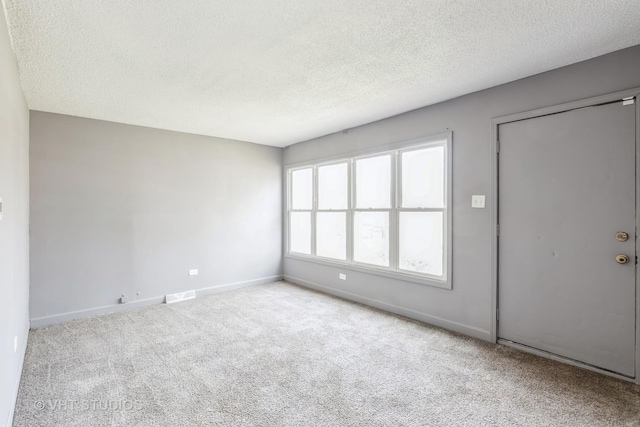 spare room featuring a textured ceiling and light carpet