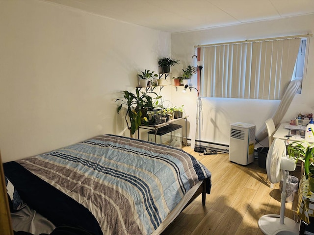 bedroom featuring baseboard heating, crown molding, and light wood-type flooring