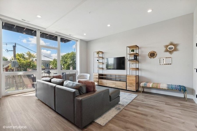 living room featuring light wood-type flooring and floor to ceiling windows