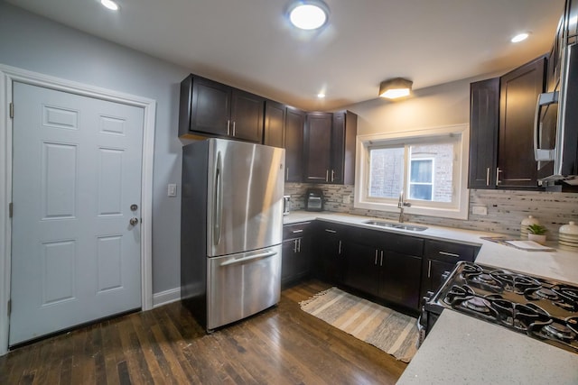 kitchen with sink, dark hardwood / wood-style floors, backsplash, dark brown cabinets, and appliances with stainless steel finishes