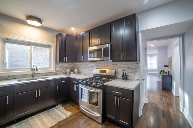 kitchen with backsplash, sink, appliances with stainless steel finishes, dark brown cabinets, and dark hardwood / wood-style flooring