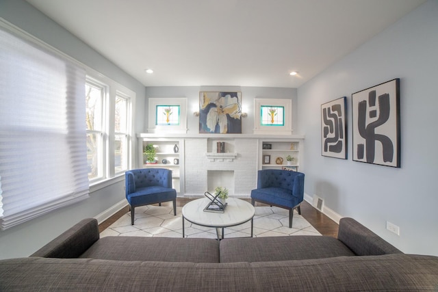 living area featuring light wood-type flooring and a brick fireplace