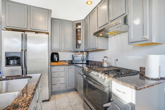 kitchen featuring appliances with stainless steel finishes, gray cabinets, light tile patterned floors, and dark stone countertops