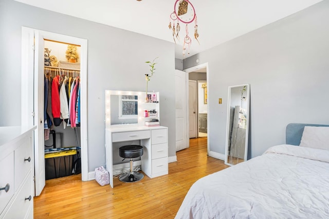 bedroom featuring a walk in closet, a closet, and light hardwood / wood-style flooring