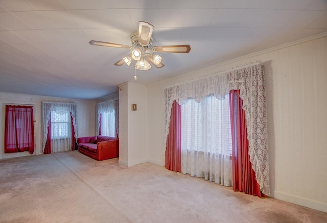 unfurnished living room with ceiling fan, light colored carpet, and ornamental molding