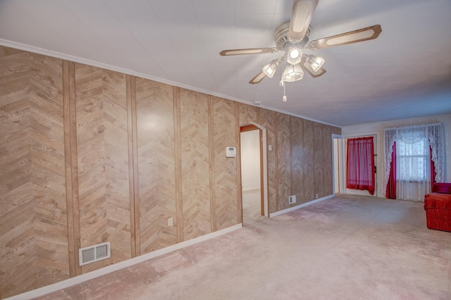 carpeted spare room with ceiling fan and wood walls