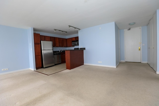 kitchen featuring stainless steel appliances, dark countertops, light colored carpet, baseboards, and open floor plan