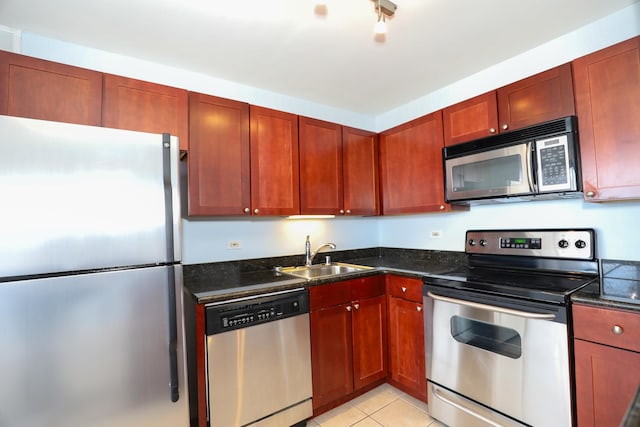 kitchen featuring stainless steel appliances, a sink, light tile patterned flooring, dark stone countertops, and dark brown cabinets