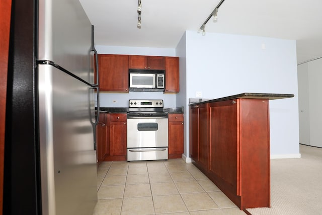 kitchen with stainless steel appliances, dark countertops, and dark brown cabinets
