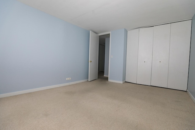 unfurnished bedroom with light carpet, baseboards, and a closet