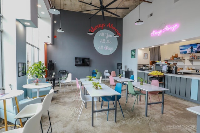 dining area featuring finished concrete flooring and a towering ceiling