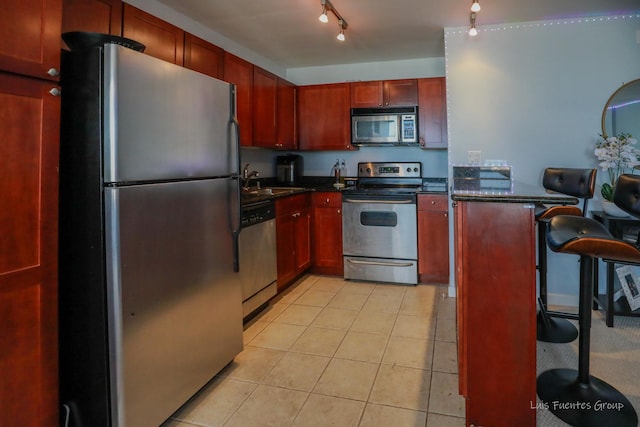 kitchen featuring sink, stainless steel appliances, rail lighting, and light tile patterned flooring