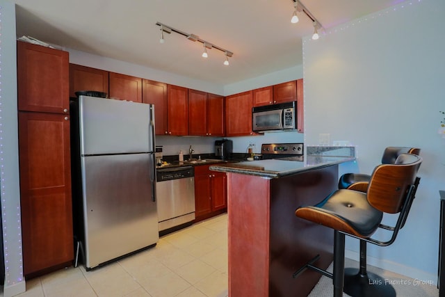 kitchen featuring a breakfast bar, rail lighting, sink, kitchen peninsula, and stainless steel appliances