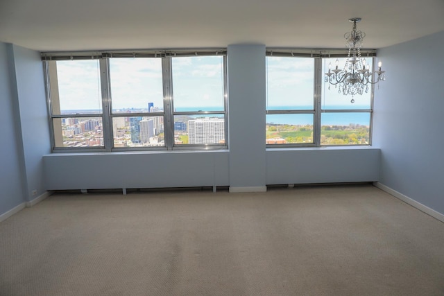 unfurnished room with a chandelier, light colored carpet, and baseboards