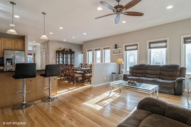 living room with ceiling fan, light hardwood / wood-style flooring, and a wealth of natural light