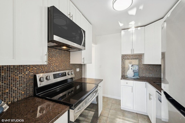 kitchen with light tile patterned floors, decorative backsplash, white cabinets, dark stone countertops, and stainless steel electric stove