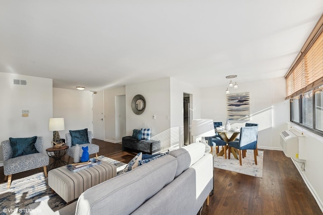 living room with dark hardwood / wood-style flooring and a wall unit AC