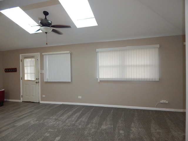 interior space with ceiling fan, vaulted ceiling with skylight, and dark wood-type flooring