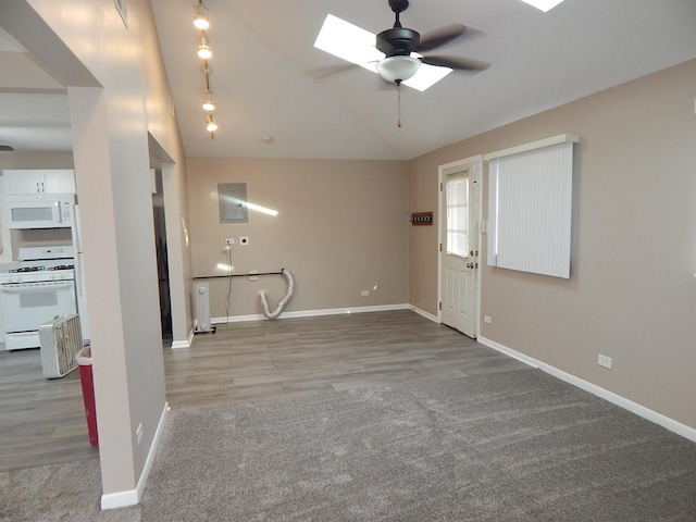 unfurnished living room featuring vaulted ceiling with skylight, ceiling fan, and hardwood / wood-style flooring