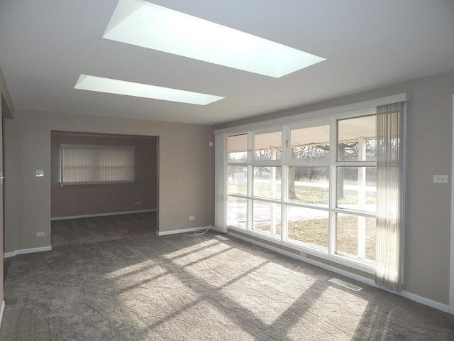 unfurnished room with dark colored carpet and a skylight