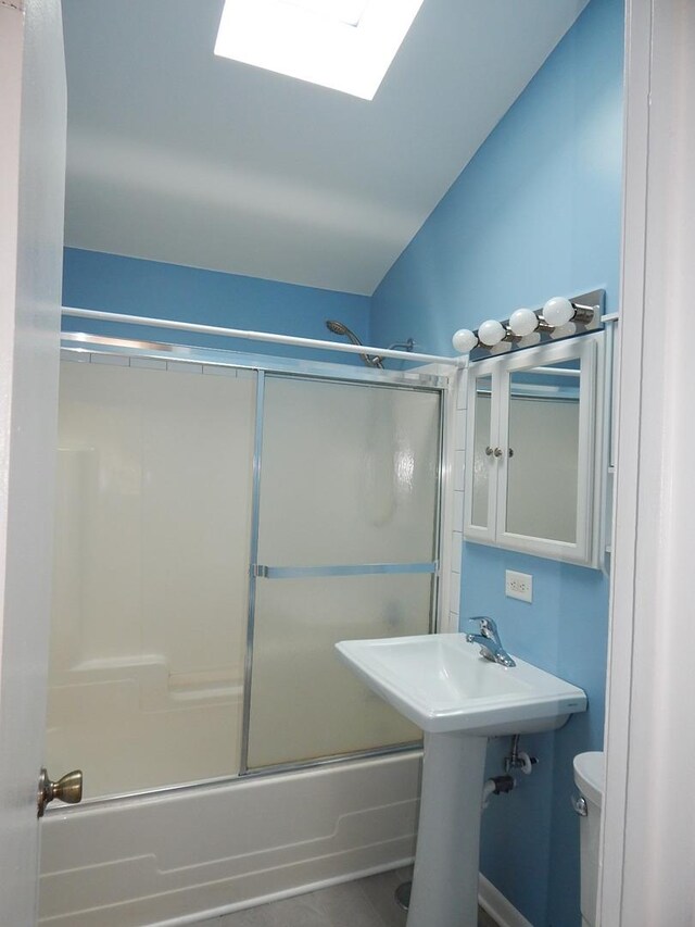 full bathroom featuring shower / bath combination with glass door, sink, vaulted ceiling, and toilet