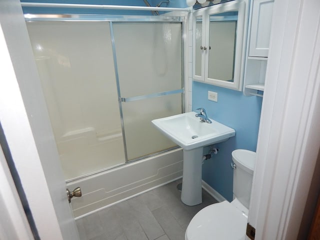 bathroom featuring toilet and combined bath / shower with glass door