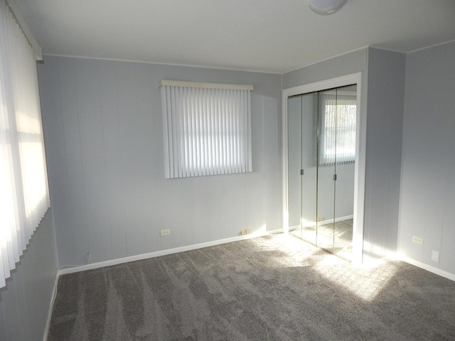 unfurnished bedroom featuring dark colored carpet and a closet