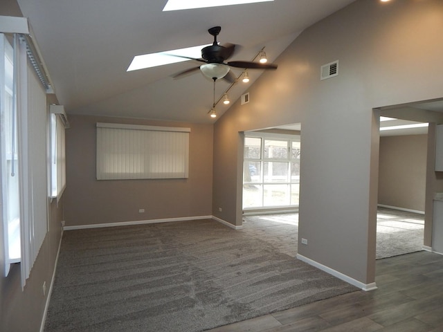 carpeted spare room with ceiling fan, high vaulted ceiling, and a skylight