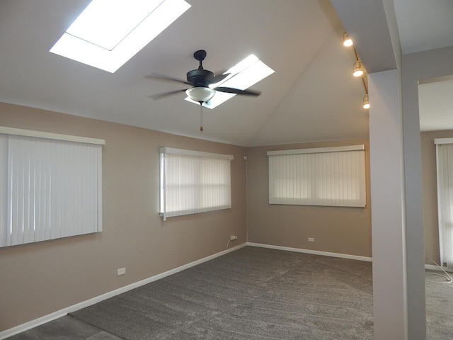 carpeted spare room with a skylight, ceiling fan, and high vaulted ceiling