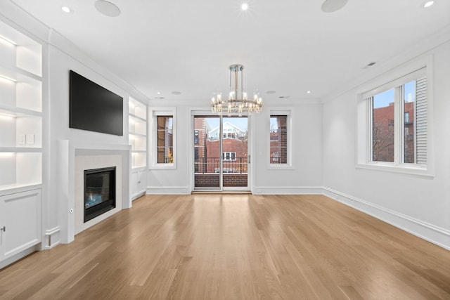 unfurnished living room featuring a chandelier, light hardwood / wood-style floors, and ornamental molding