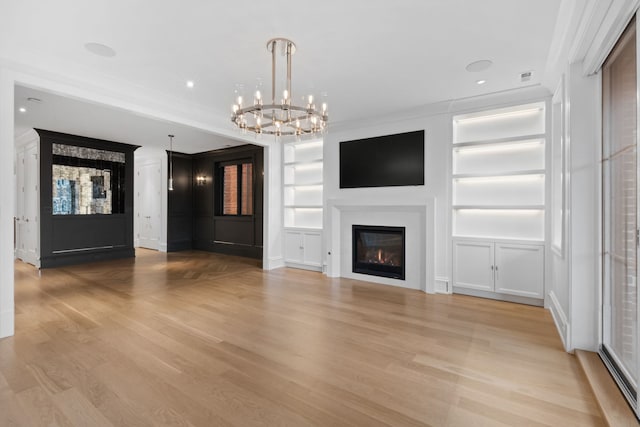 unfurnished living room featuring a notable chandelier, built in shelves, ornamental molding, and light hardwood / wood-style flooring