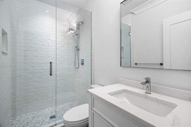 bathroom with vanity, toilet, and a shower with door